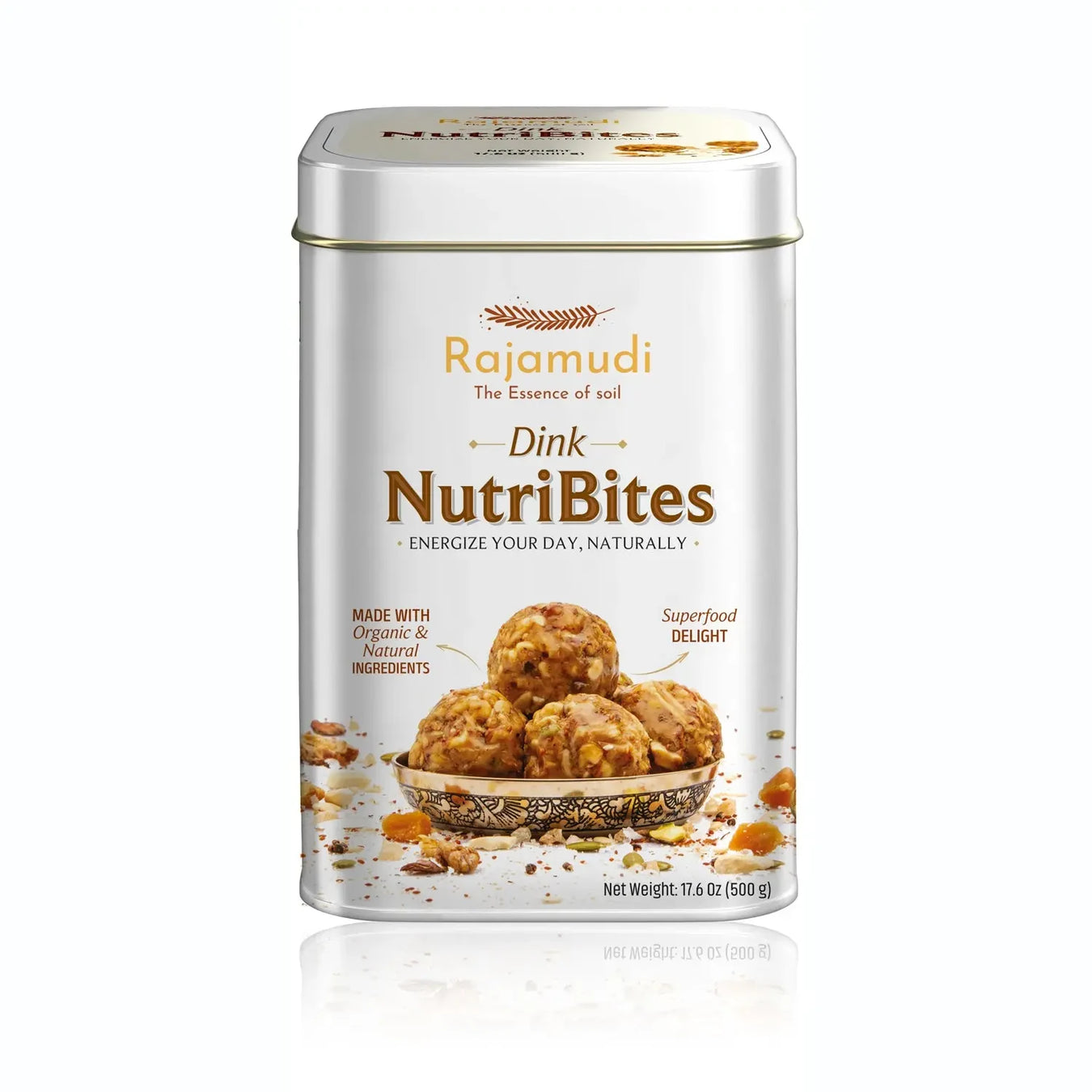 A tin of Rajamudi Dink NutriBites energy bites, with the product name and benefits listed on the label, surrounded by dry fruits such as almonds and seeds, and individual bites visible in the foreground.
